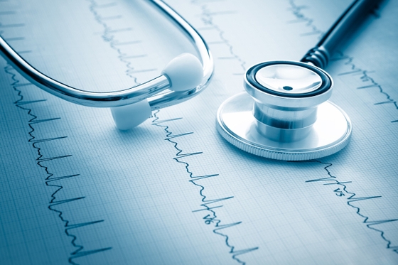 A stethoscope and a heartbeat symbol on a paper, representing medical examination and monitoring.