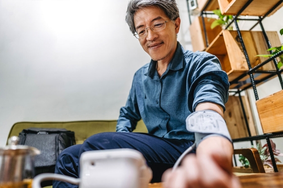 Man wearing glasses administering himself a blood pressure test