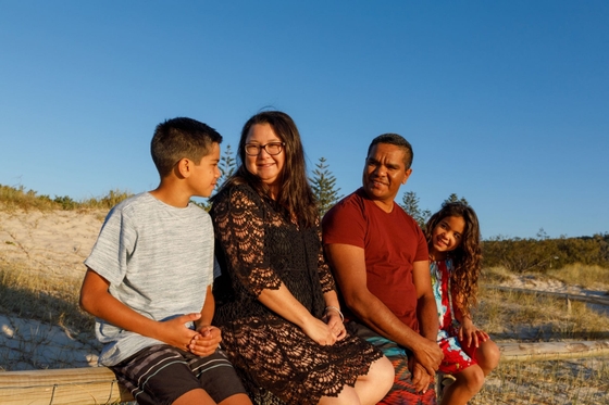 A multi-racial family sitting in the sunshine on the beach