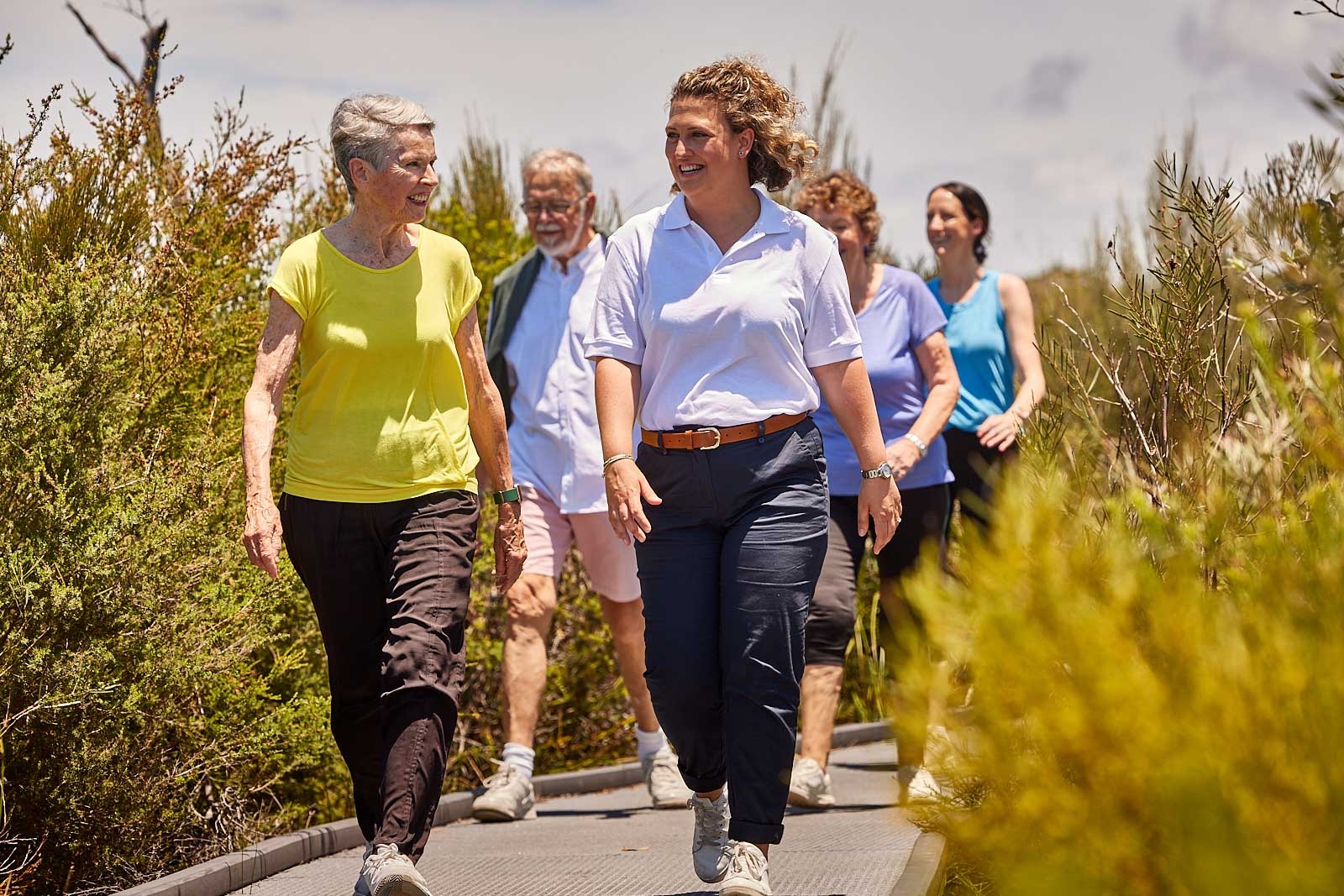 Two women walking on a path, one wearing a blue hat.